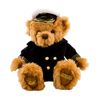 Stuffed teddy bear in a captain's outfit with a hat on a white background