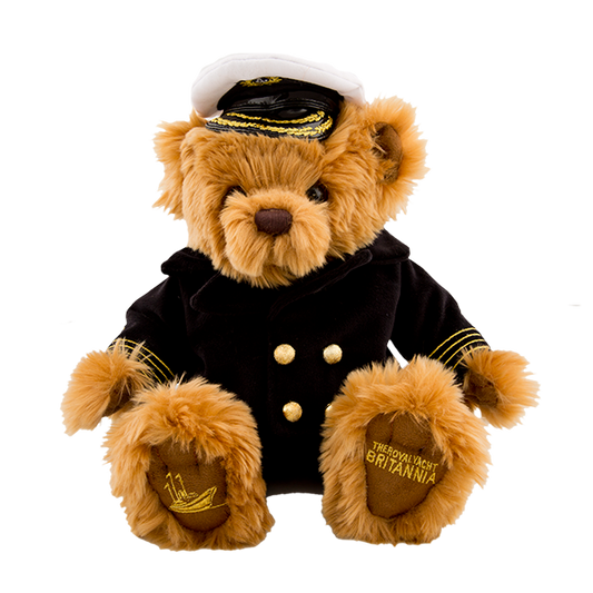 Stuffed teddy bear in a captain's outfit with a hat on a white background